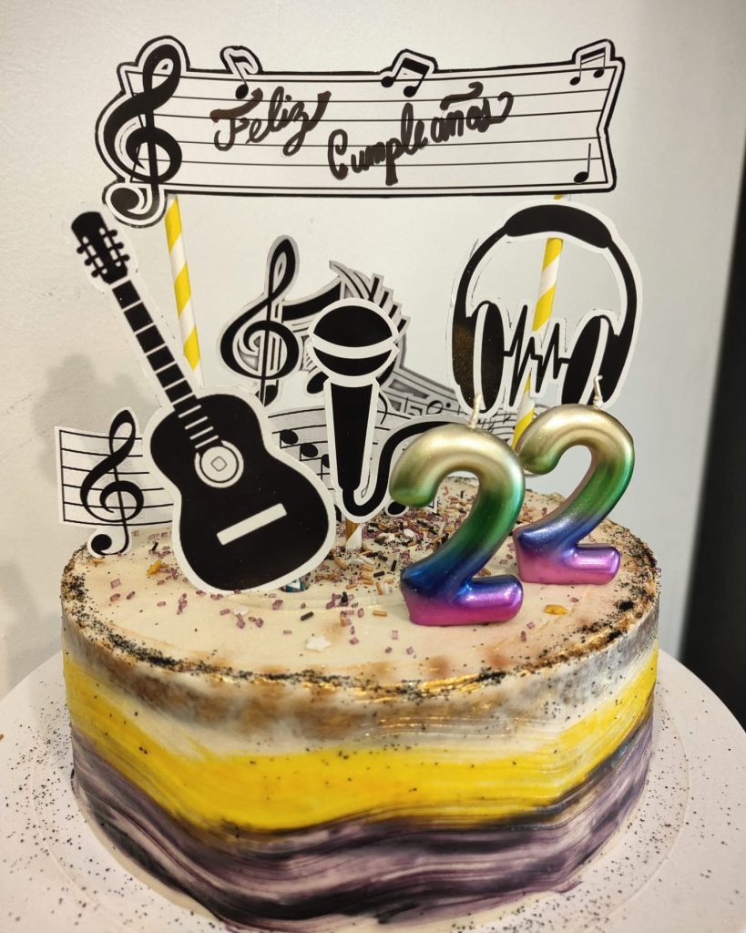 Tarta decorada con temática musical, topper de Feliz Cumpleaños y números 22, elaborada como tarta personalizada en Sevilla.